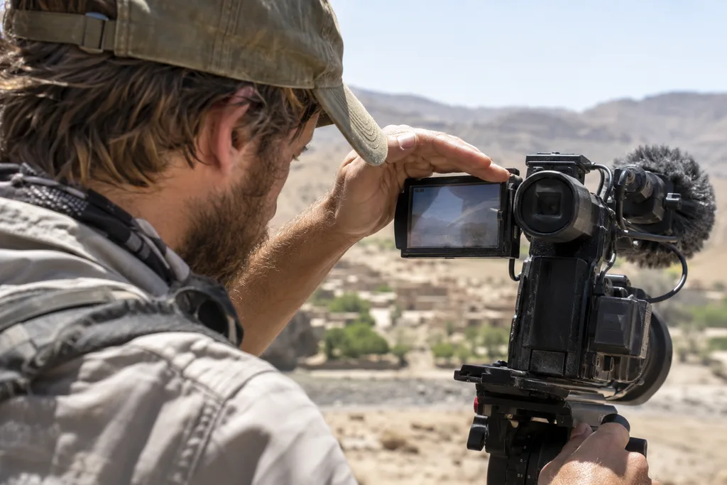 Filmmaker shading a camera monitor from harsh sunlight